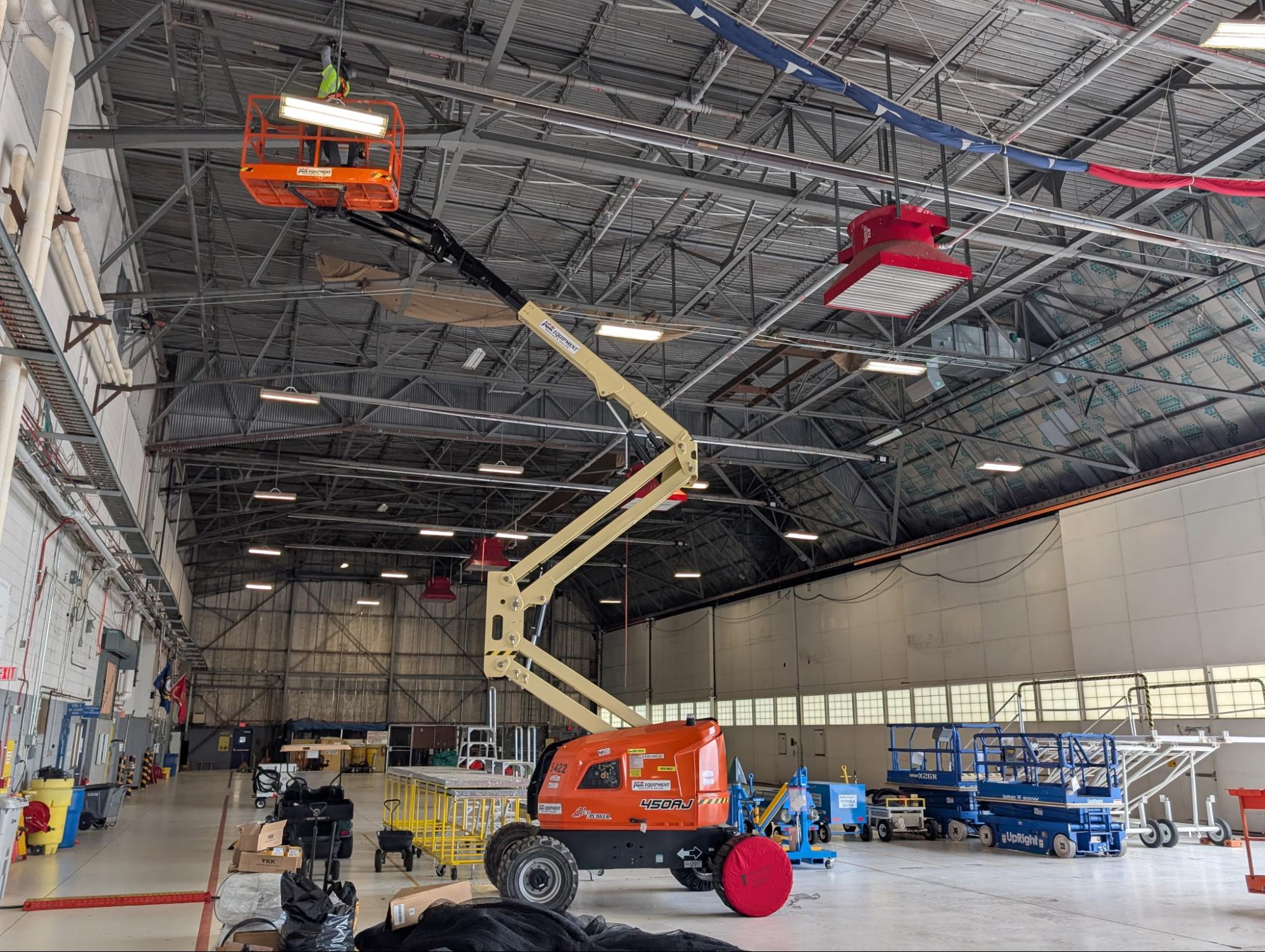 Elite Bird Management technicians installing bird netting inside a large warehouse using an aerial lift to prevent birds from nesting and roosting